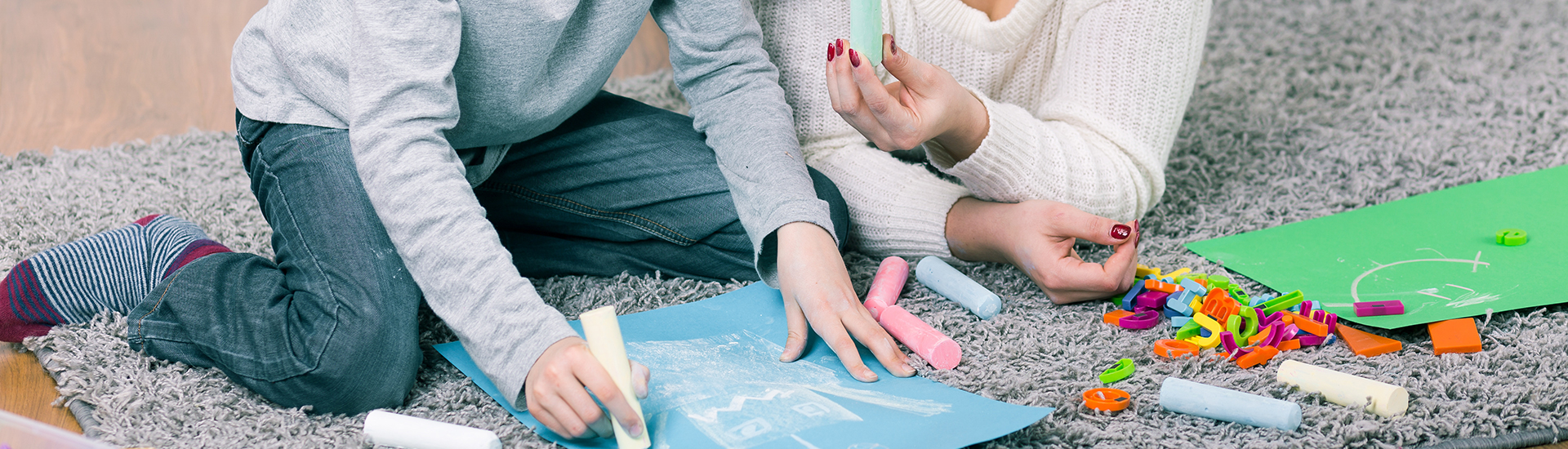 Boy and woman drawing a picture, lying on carpet, panorama.